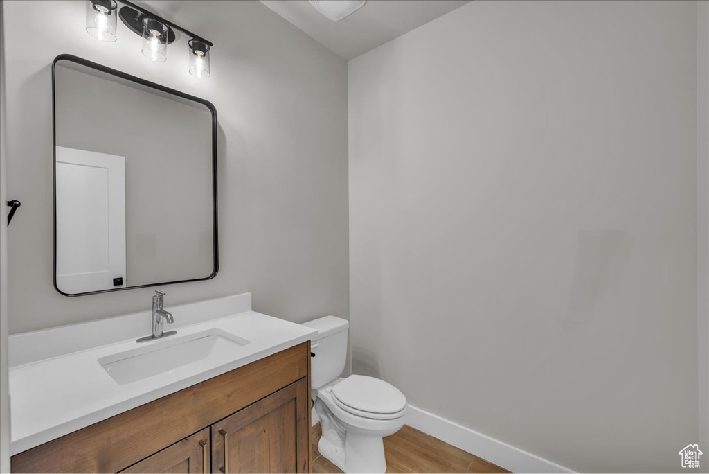 Bathroom featuring vanity, toilet, and baseboards