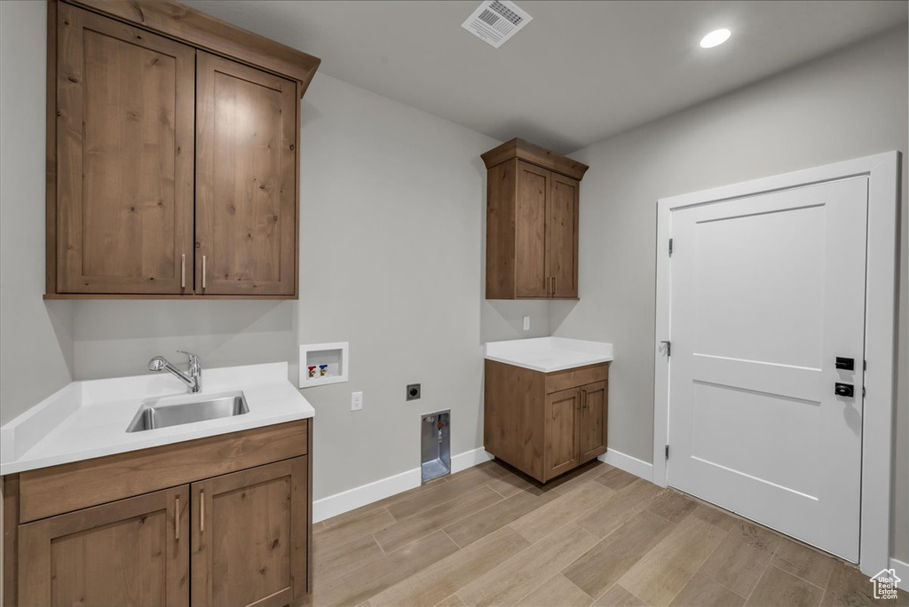 Clothes washing area featuring a sink, light wood-type flooring, visible vents, electric dryer hookup, and washer hookup