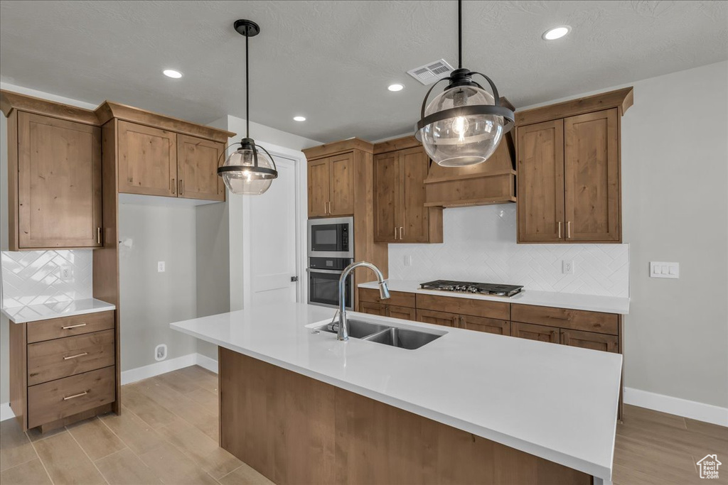 Kitchen with baseboards, visible vents, a sink, brown cabinets, and stainless steel appliances