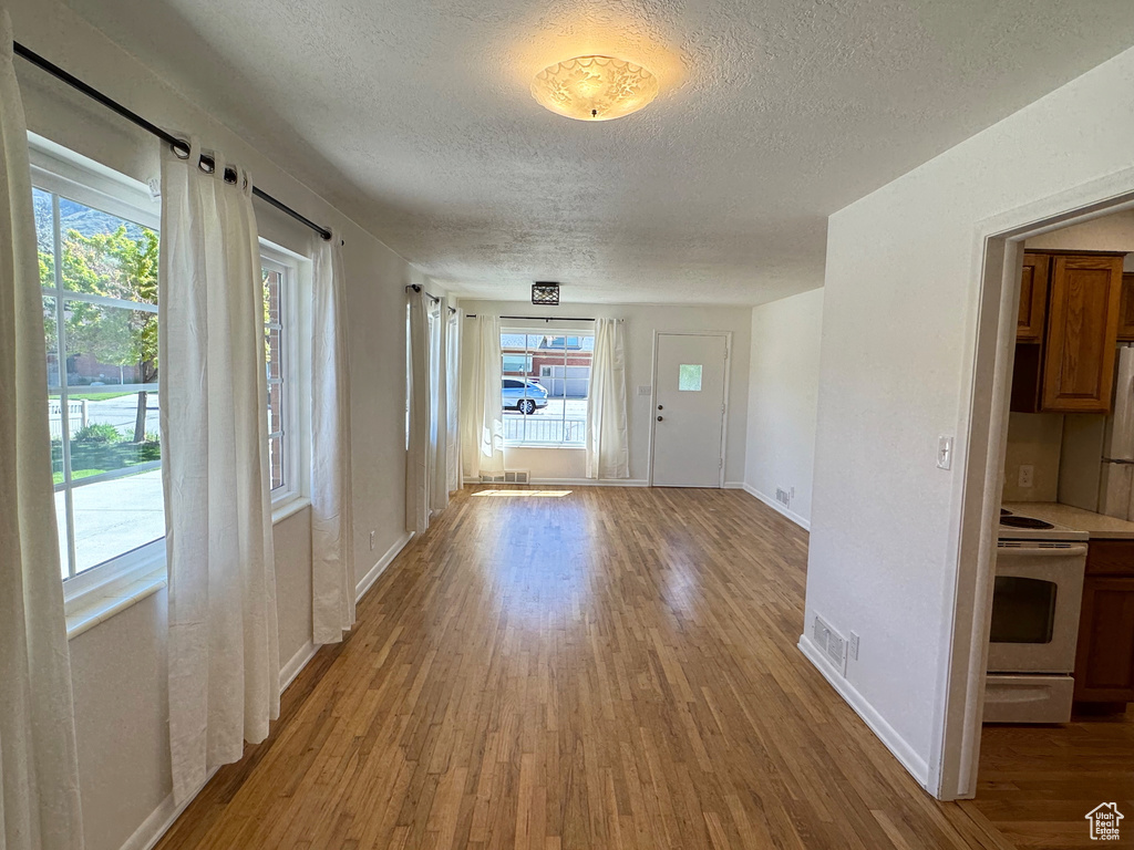 Interior space featuring a textured ceiling, baseboards, visible vents, and wood finished floors