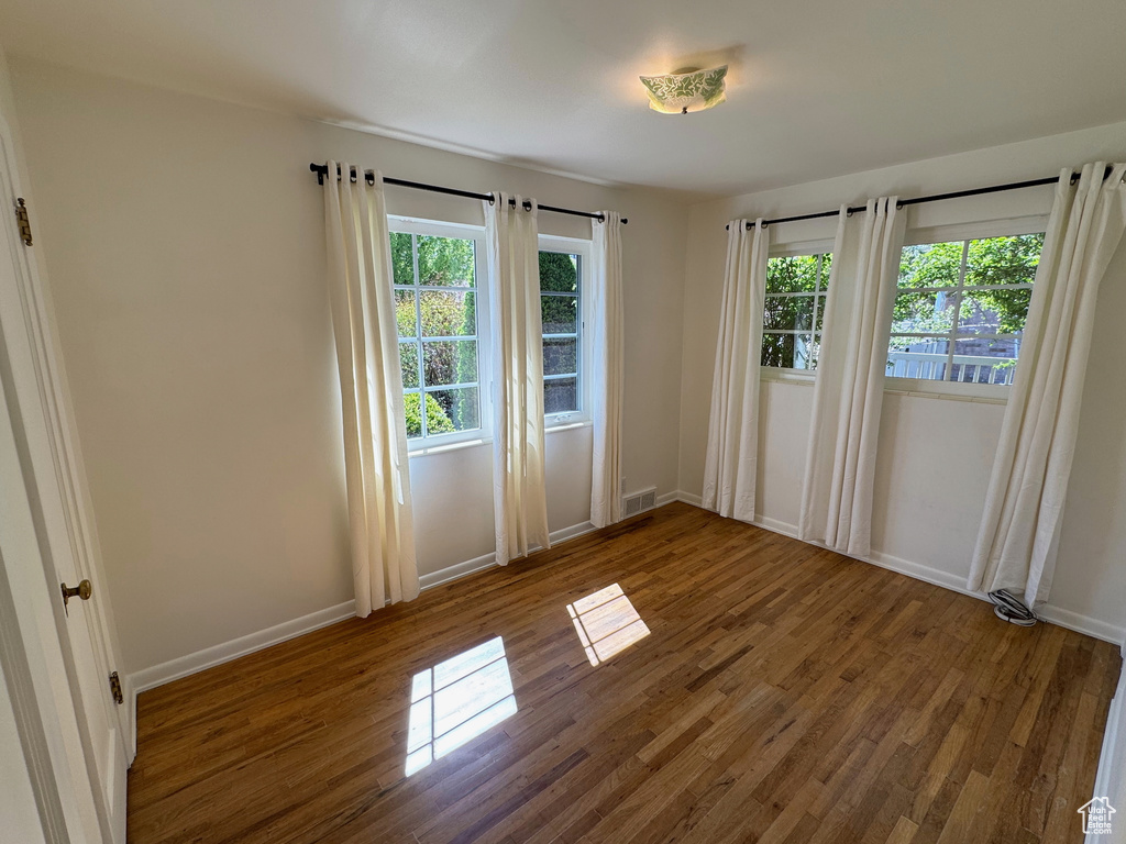 Unfurnished room with baseboards, visible vents, and wood finished floors