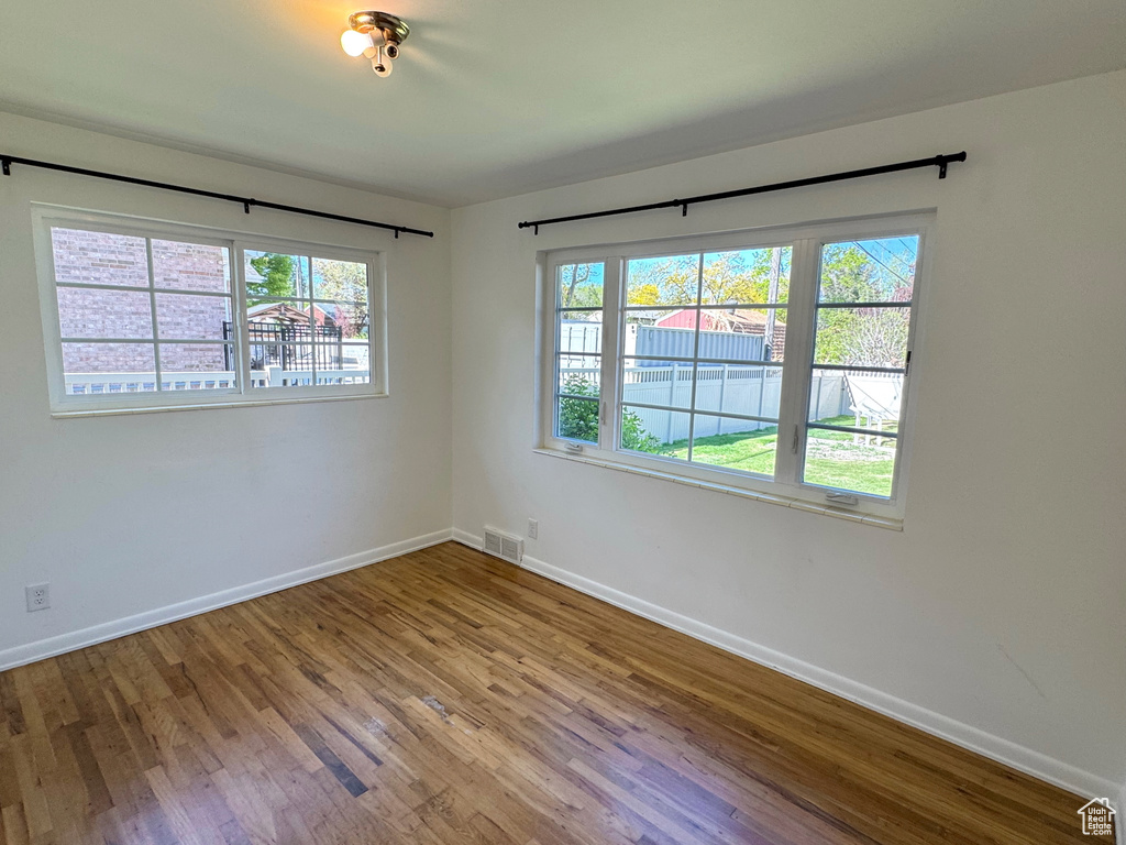 Unfurnished room featuring wood finished floors, visible vents, and baseboards