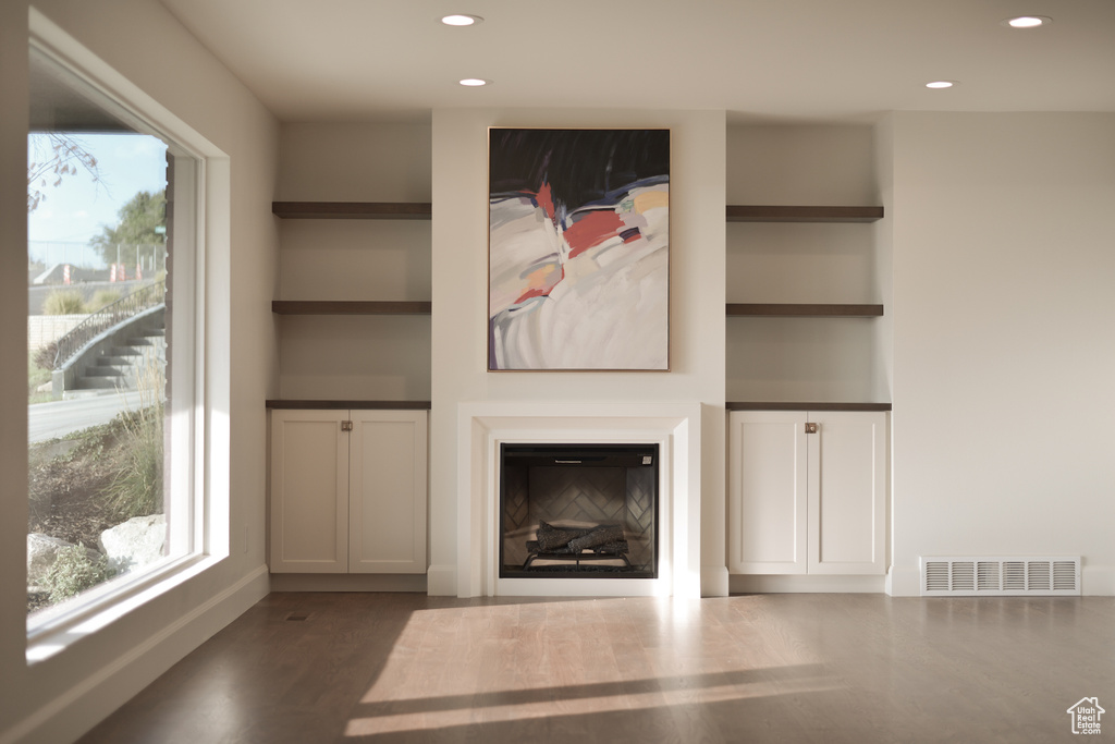 Unfurnished living room with visible vents, wood finished floors, a glass covered fireplace, and recessed lighting