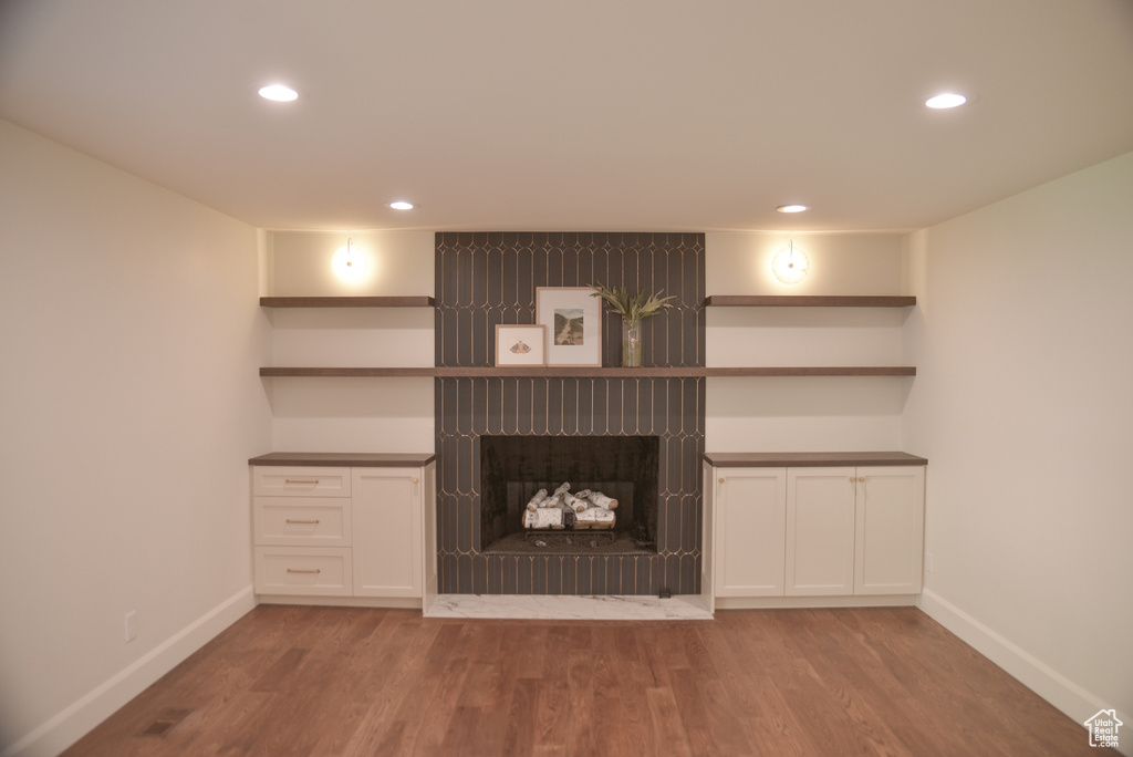 Unfurnished living room with a fireplace, recessed lighting, baseboards, and wood finished floors