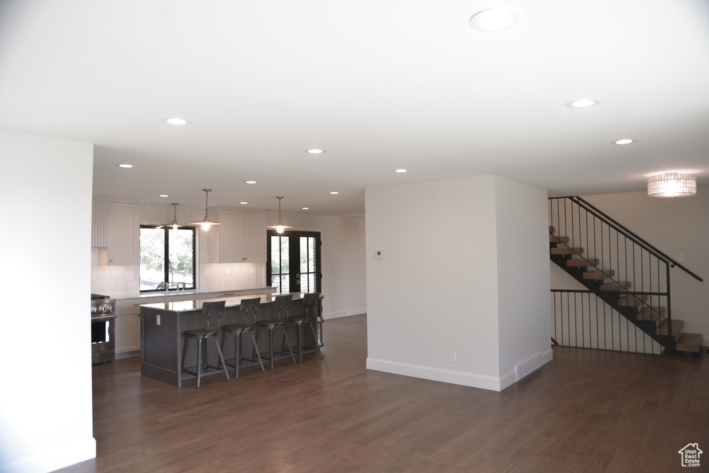 Living room featuring stairs, dark wood-style flooring, baseboards, and recessed lighting