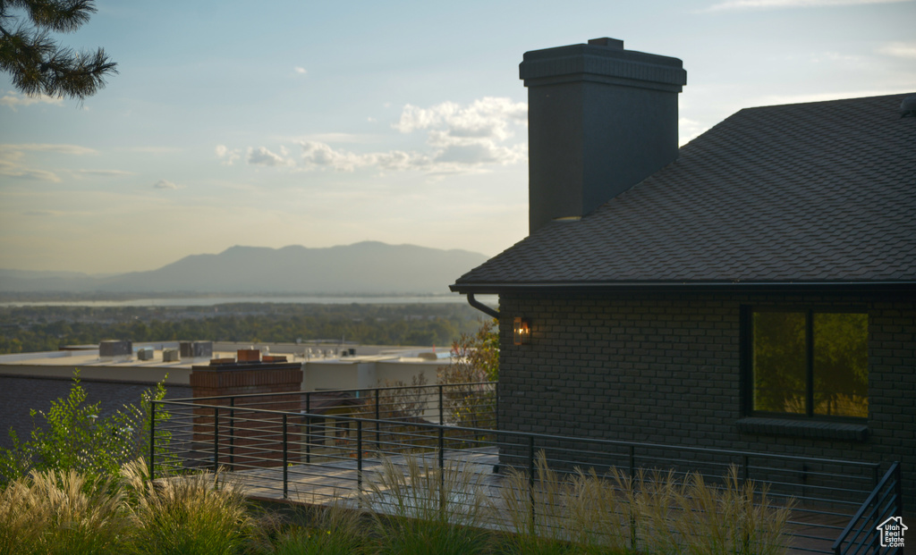 Exterior space featuring a shingled roof, a mountain view, brick siding, and a chimney