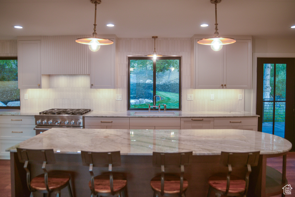Kitchen with a sink, decorative backsplash, gas range, and white cabinets