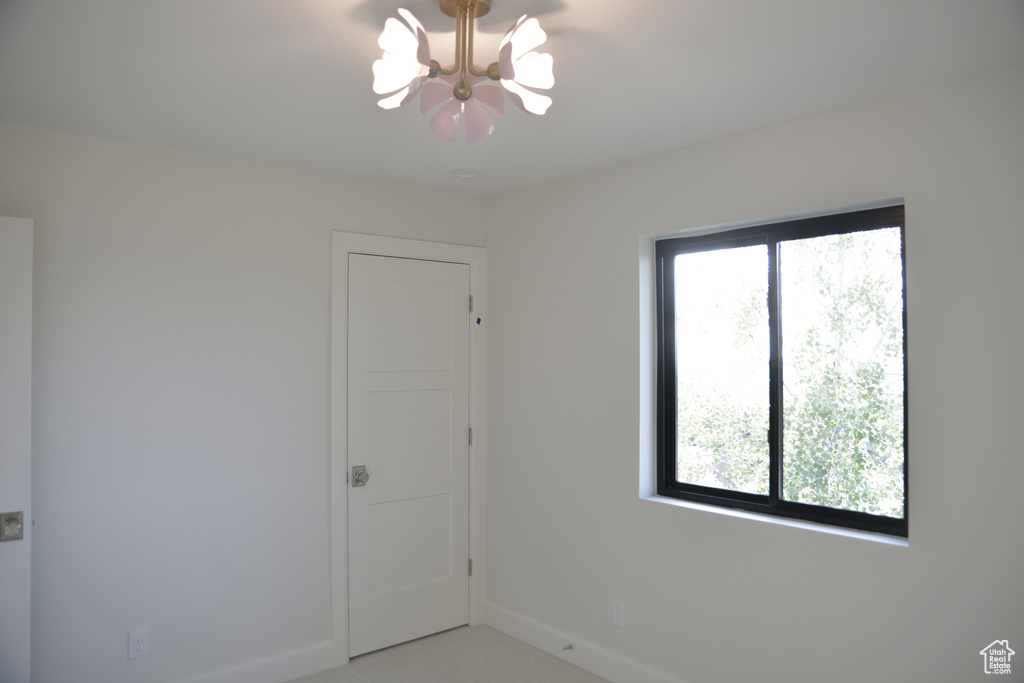 Unfurnished room with baseboards, an inviting chandelier, and carpet