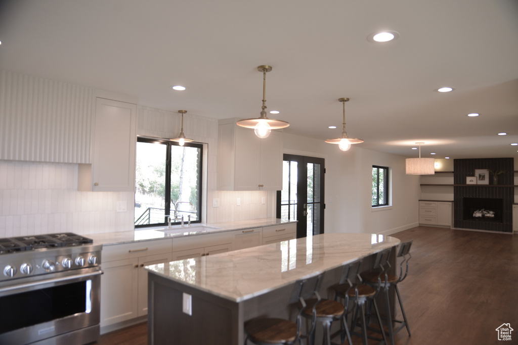 Kitchen featuring a sink, stainless steel range with gas stovetop, recessed lighting, backsplash, and white cabinets