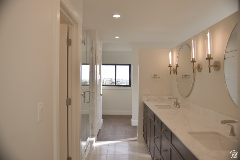 Full bath with double vanity, tile patterned floors, baseboards, and a sink