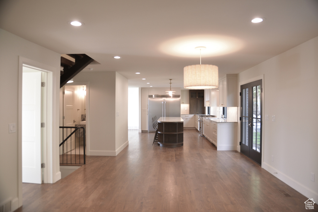 Kitchen with high end appliances, light countertops, dark wood finished floors, and a kitchen island