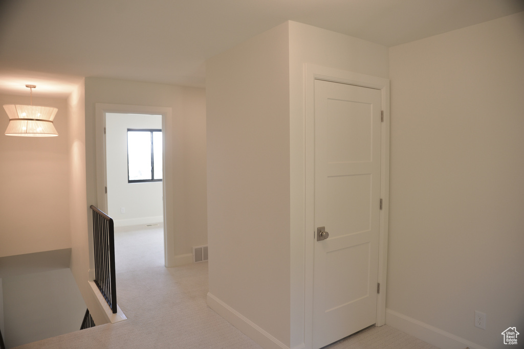 Hallway featuring visible vents, an upstairs landing, and baseboards