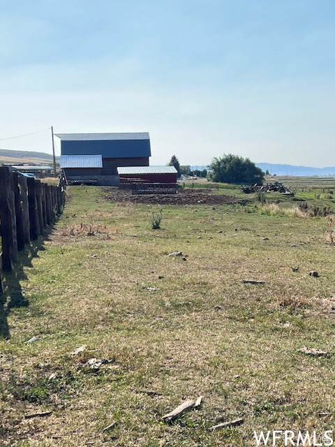 View of yard with fence, a rural view, an outbuilding, and an outdoor structure