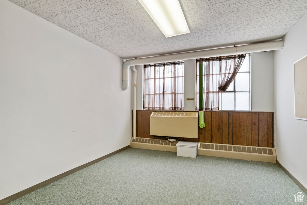 Carpeted spare room with a textured ceiling and radiator
