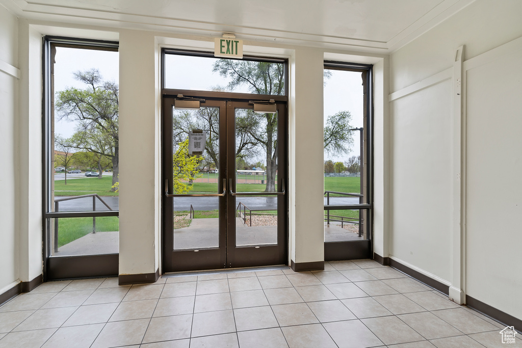Doorway featuring baseboards, light tile patterned flooring, french doors, and crown molding