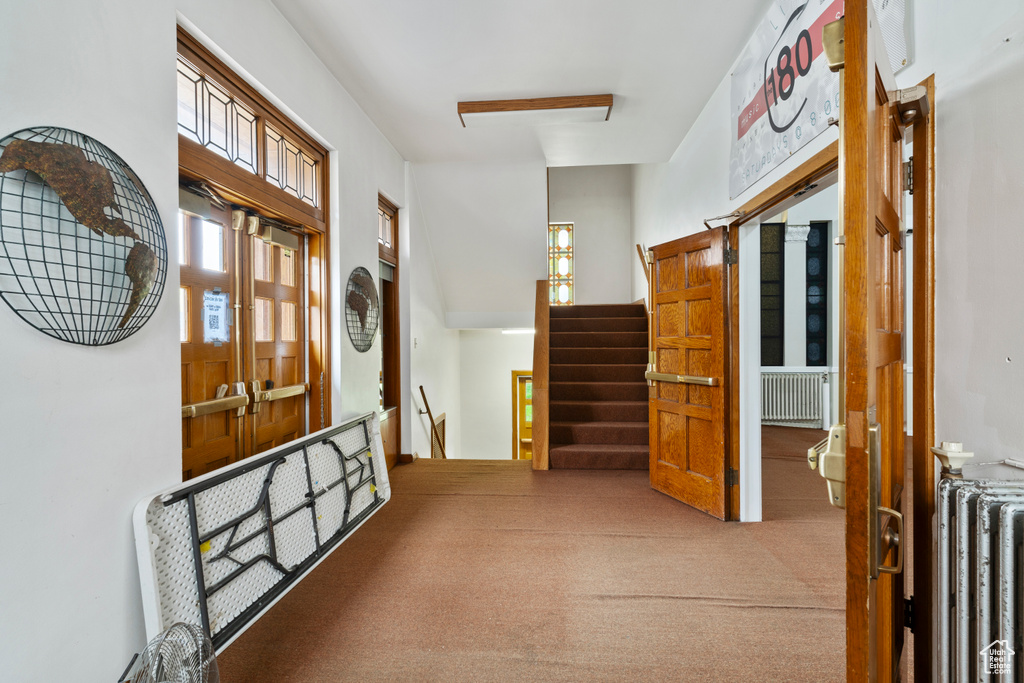 Hall featuring stairway, radiator, and carpet floors
