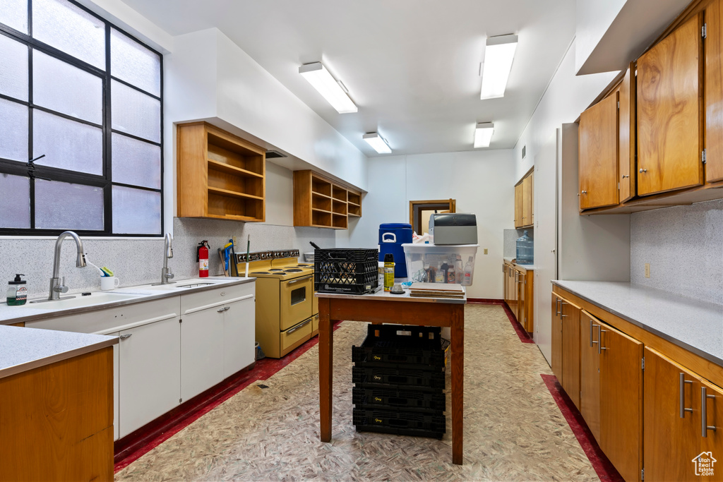 Kitchen with light countertops, a sink, decorative backsplash, and white electric stove