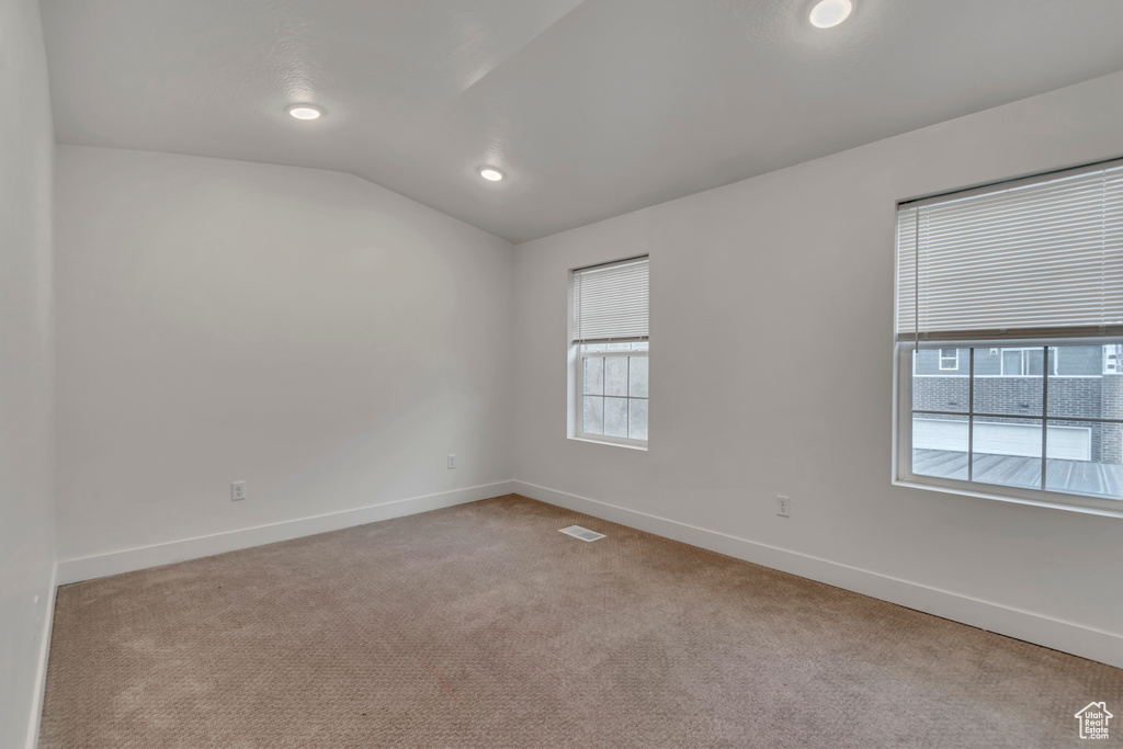 Carpeted spare room with baseboards, visible vents, recessed lighting, and vaulted ceiling