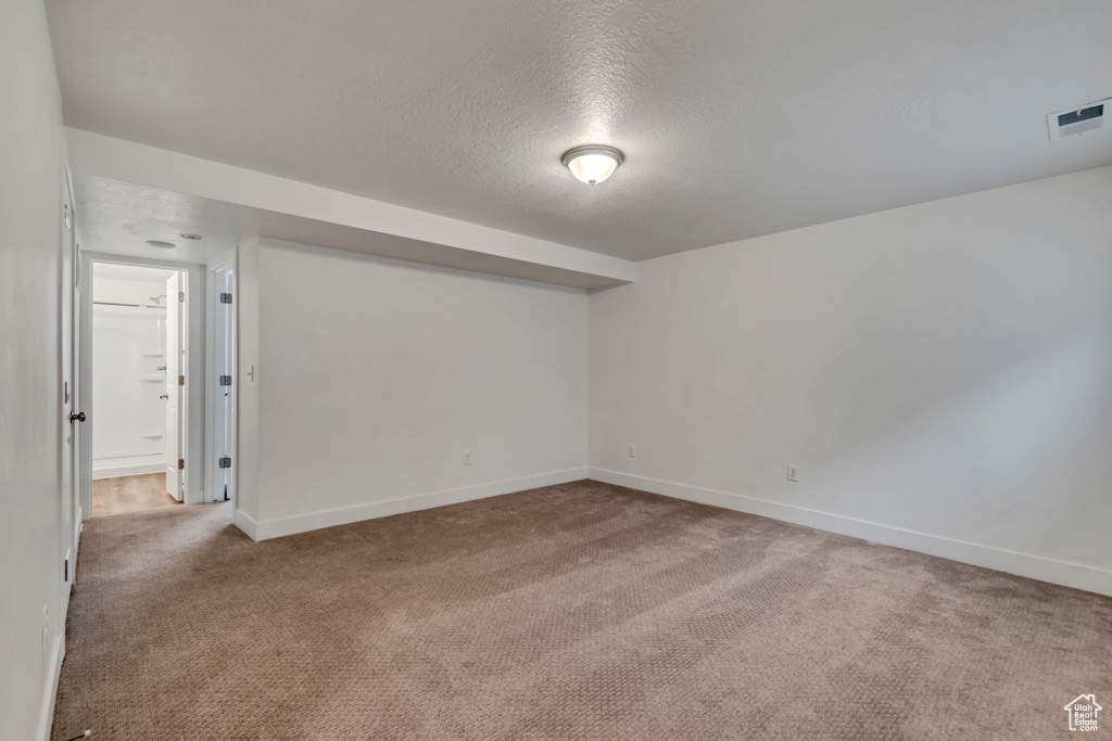Carpeted spare room with baseboards, visible vents, and a textured ceiling
