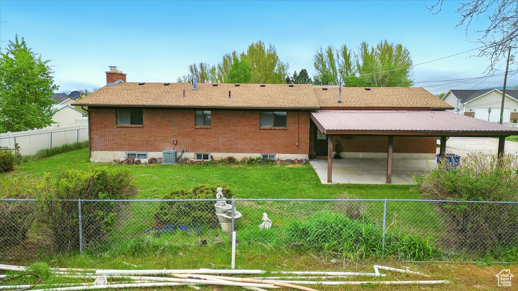 Back of property with a chimney, a lawn, a patio, central air condition unit, and a fenced backyard