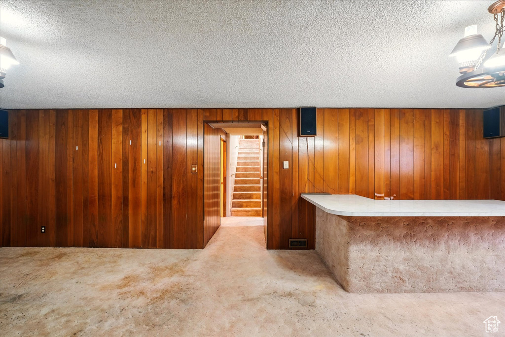 Bar featuring a dry bar, stairway, wooden walls, and a textured ceiling