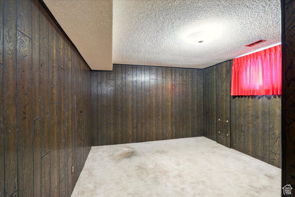 Spare room featuring a textured ceiling, wooden walls, and visible vents