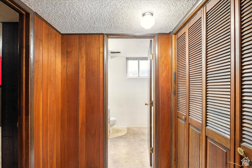 Hallway with a textured ceiling, carpet, and visible vents