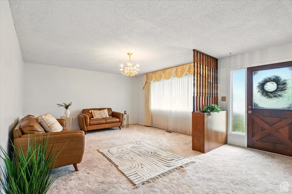 Carpeted living area featuring a chandelier and a textured ceiling