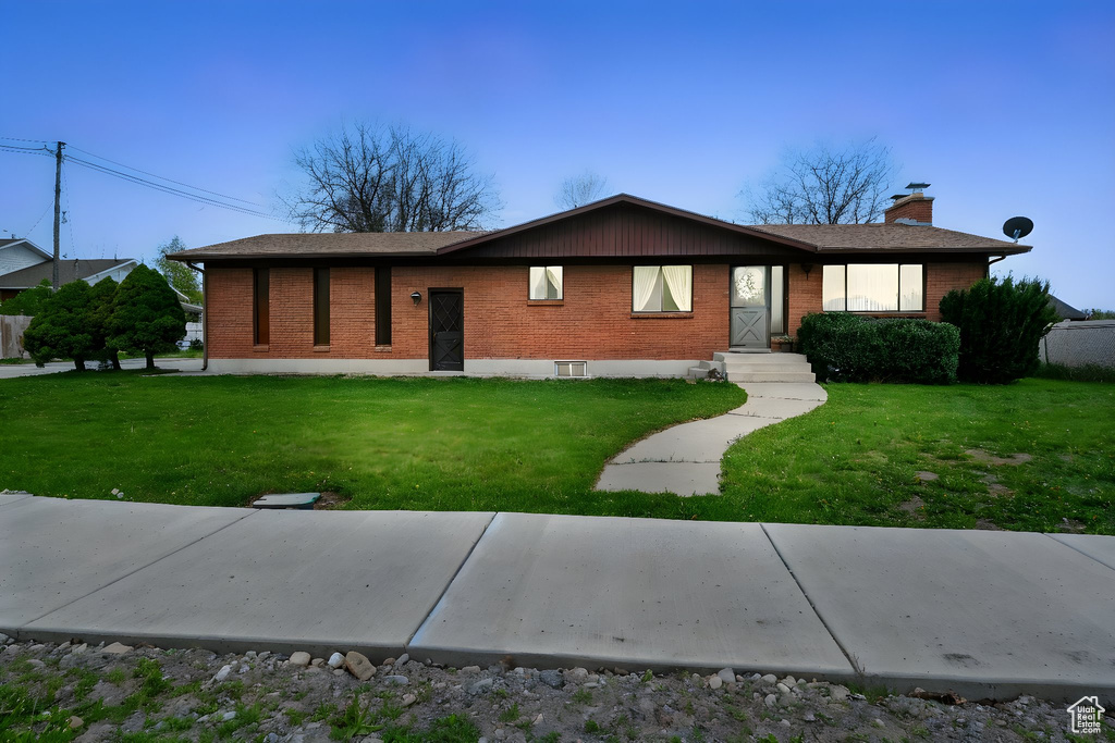 Ranch-style house with a chimney, a front lawn, and brick siding