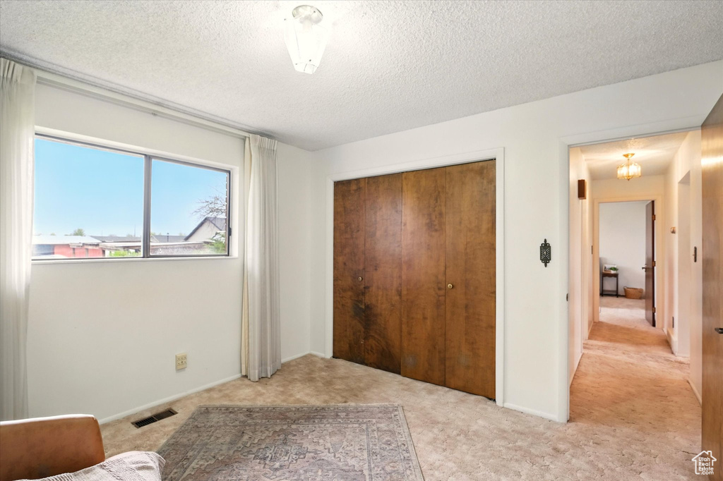 Bedroom featuring a closet, a textured ceiling, visible vents, baseboards, and light colored carpet