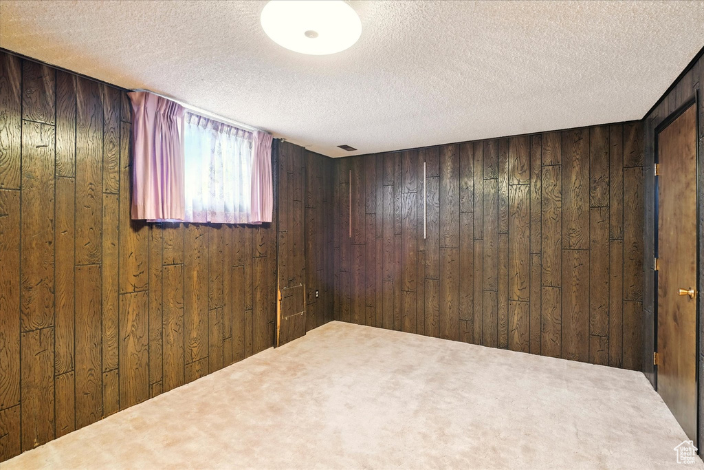 Spare room with a textured ceiling, wooden walls, and carpet floors