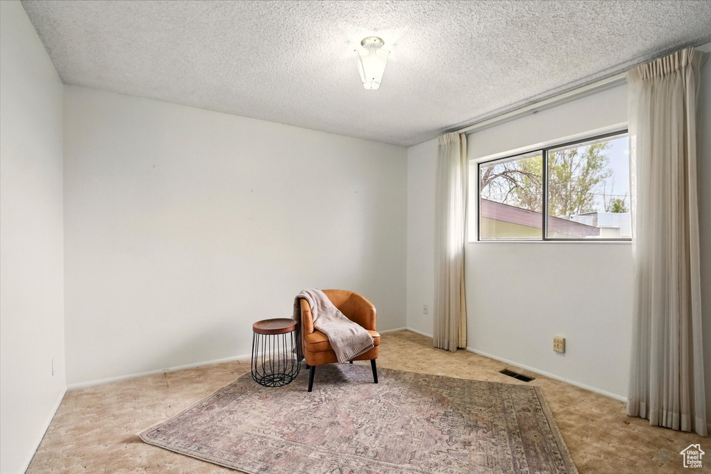 Unfurnished room featuring carpet flooring, a textured ceiling, and visible vents