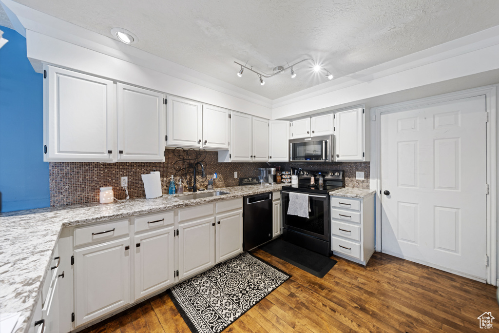 Kitchen with black appliances, a sink, dark wood-style flooring, white cabinetry, and a textured ceiling