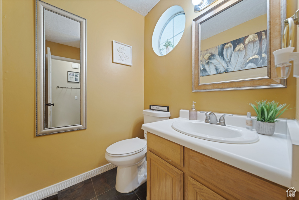 Bathroom featuring toilet, baseboards, tile patterned floors, and vanity
