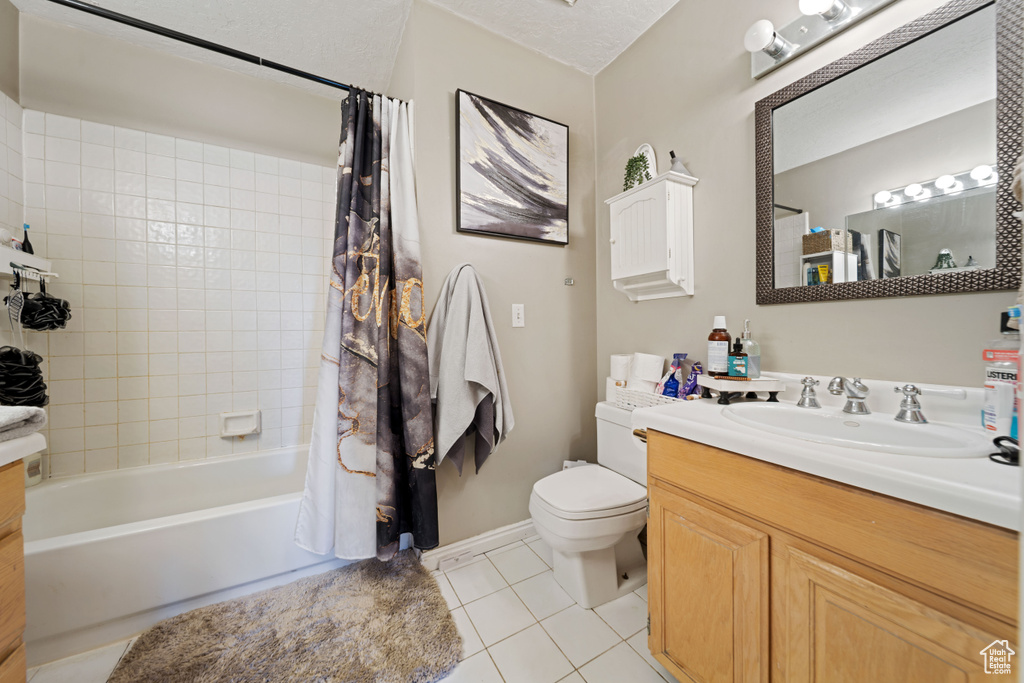 Full bath featuring tile patterned flooring, toilet, shower / bathtub combination with curtain, vanity, and baseboards