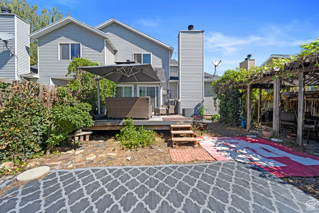 Rear view of house with a wooden deck, a pergola, fence, an outdoor living space, and a patio area