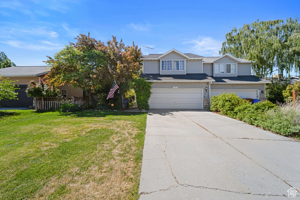 View of front of home with a garage, concrete driveway, and a front lawn