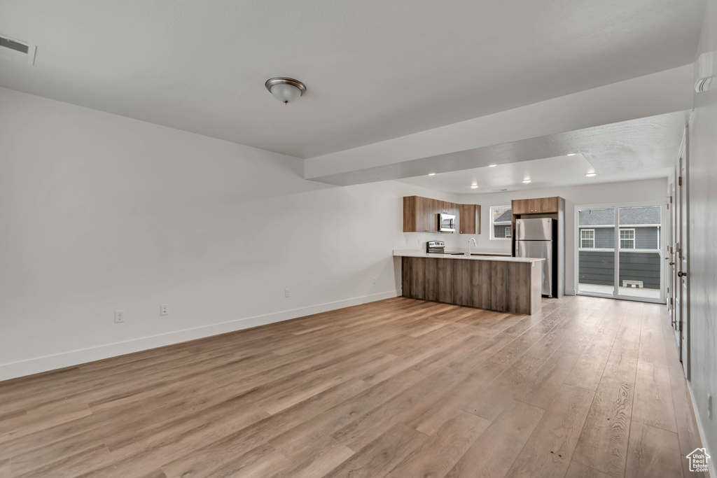 Unfurnished living room with baseboards, visible vents, and light wood-style floors