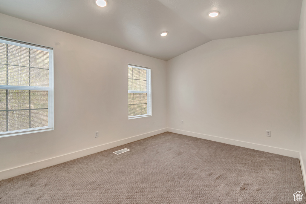 Carpeted spare room featuring visible vents, baseboards, lofted ceiling, and recessed lighting