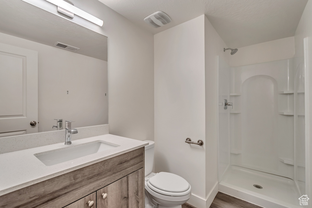 Full bathroom with walk in shower, toilet, visible vents, and vanity