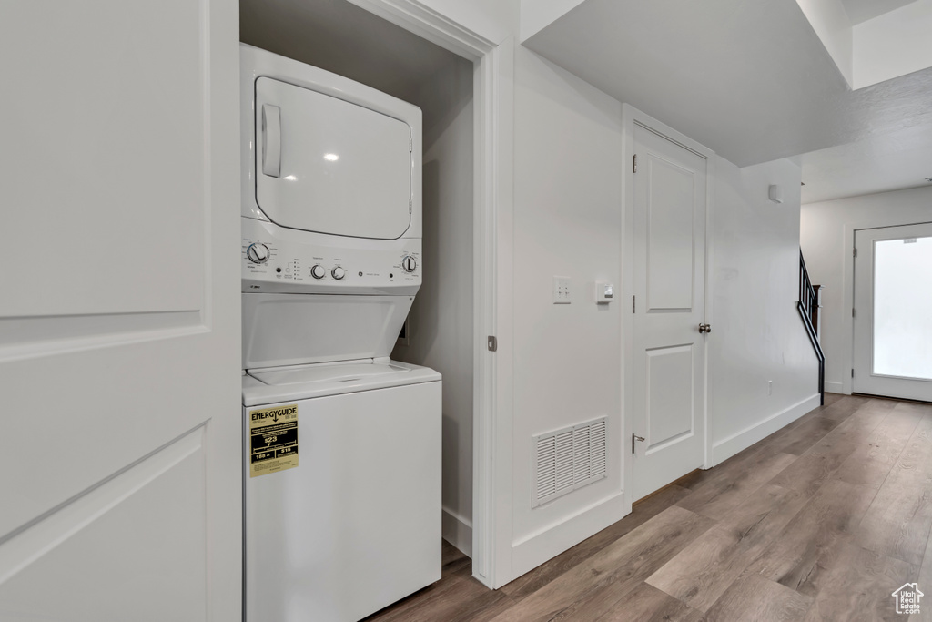 Laundry area featuring visible vents, laundry area, stacked washer / dryer, and wood finished floors
