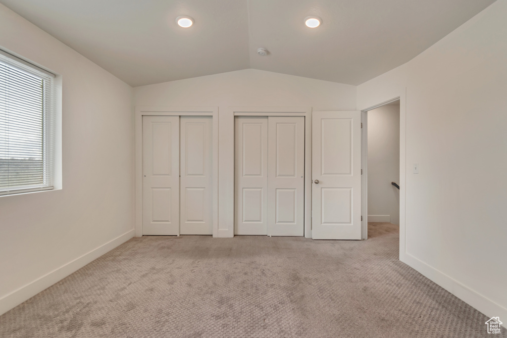 Unfurnished bedroom with carpet, recessed lighting, vaulted ceiling, two closets, and baseboards