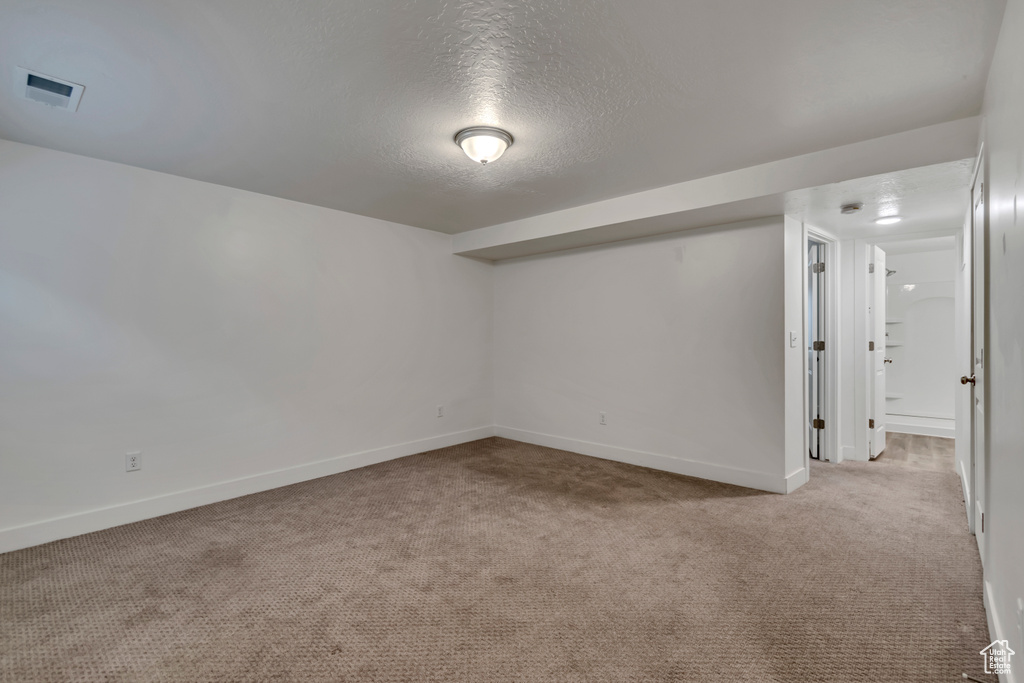 Finished below grade area featuring baseboards, a textured ceiling, and carpet