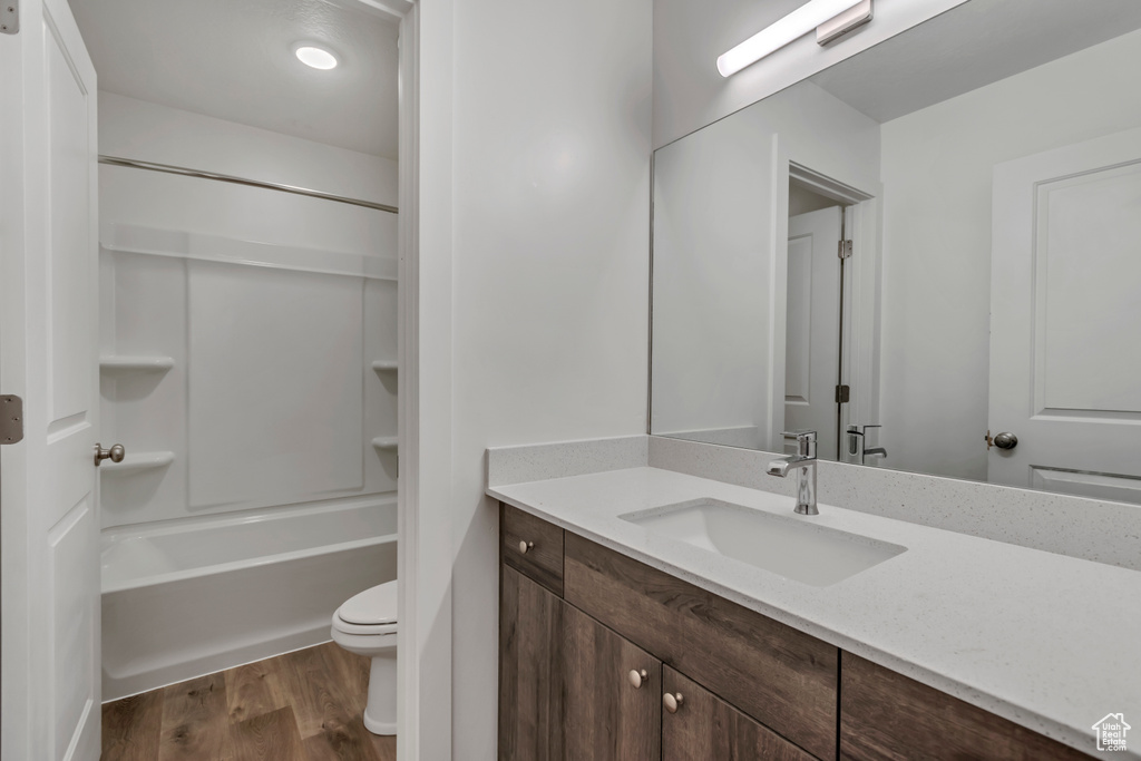 Bathroom with shower / bath combination, vanity, toilet, and wood finished floors