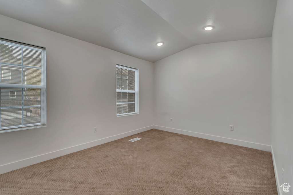 Carpeted spare room with lofted ceiling, a wealth of natural light, baseboards, and visible vents