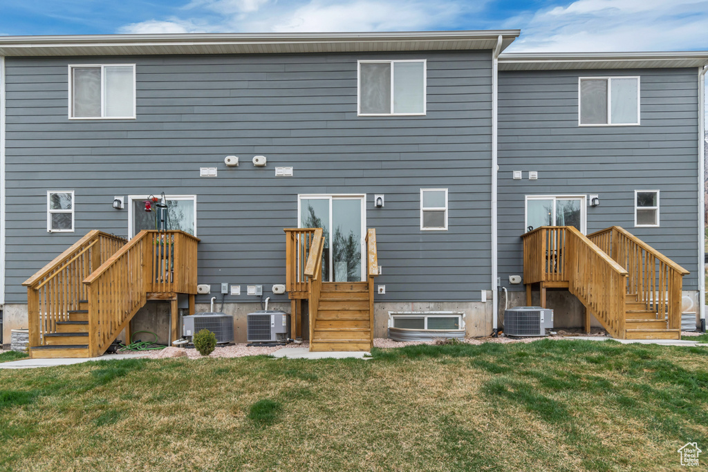 Back of property featuring central AC unit and a lawn