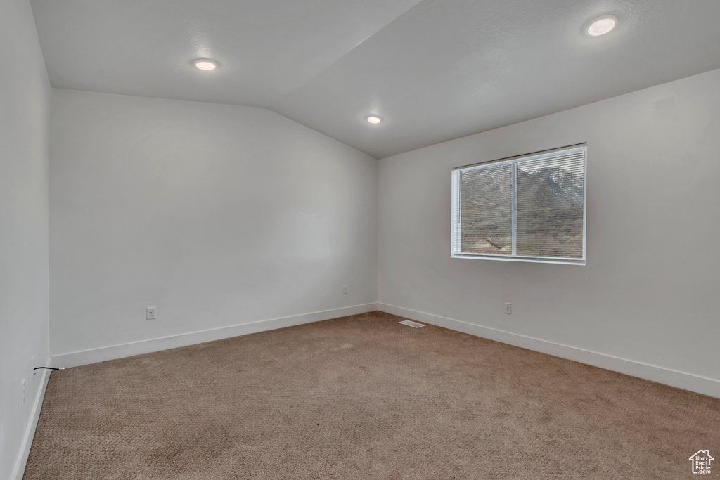 Carpeted spare room featuring vaulted ceiling, baseboards, and recessed lighting