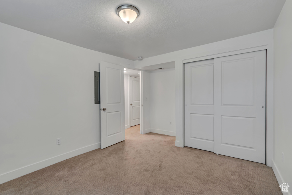 Unfurnished bedroom with a textured ceiling, carpet floors, baseboards, and a closet