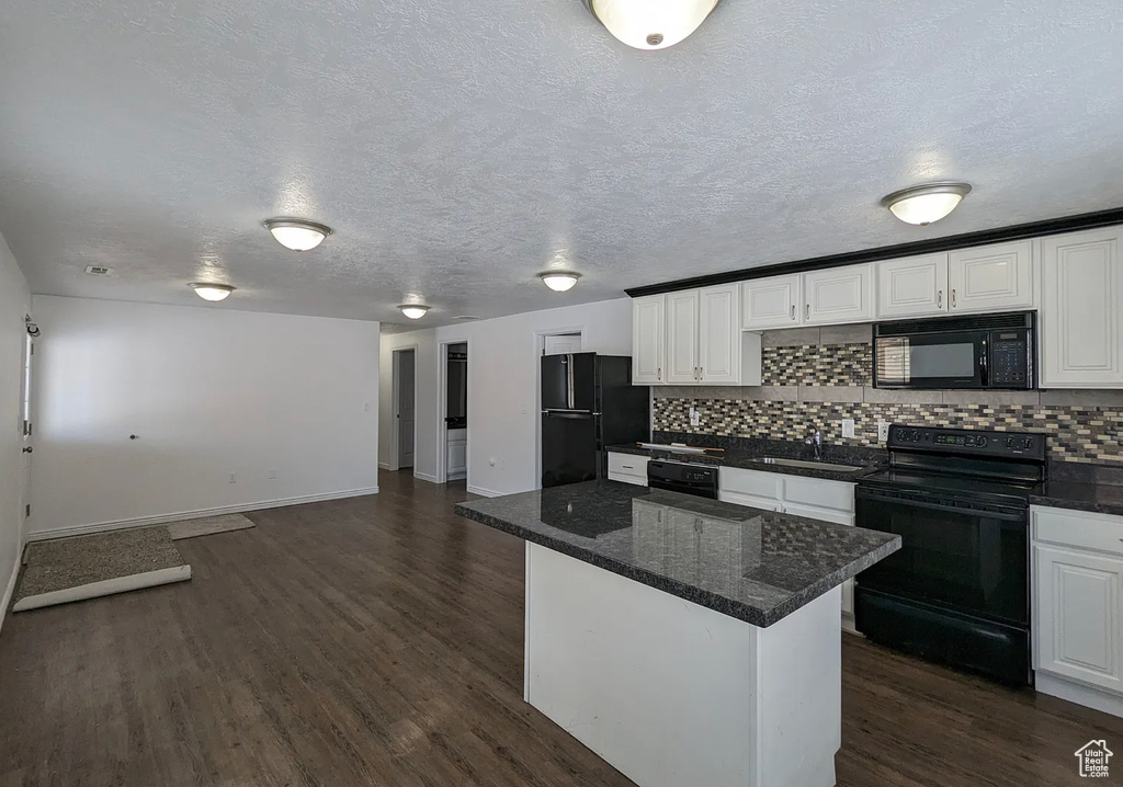 Kitchen with a sink, black appliances, dark wood-style flooring, decorative backsplash, and white cabinets