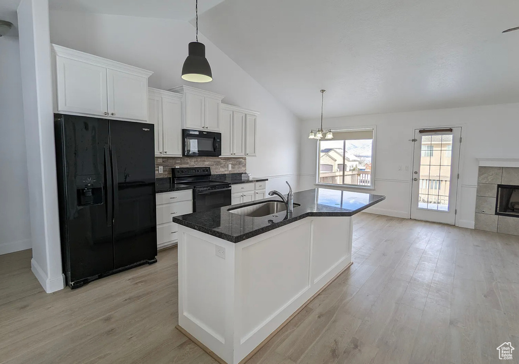 Kitchen with a sink, tasteful backsplash, light wood-type flooring, black appliances, and white cabinets
